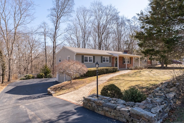 ranch-style home with an attached garage, brick siding, driveway, and a chimney