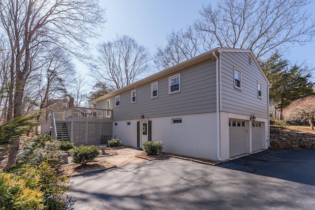 view of front of home with an attached garage, stairway, a wooden deck, stucco siding, and driveway