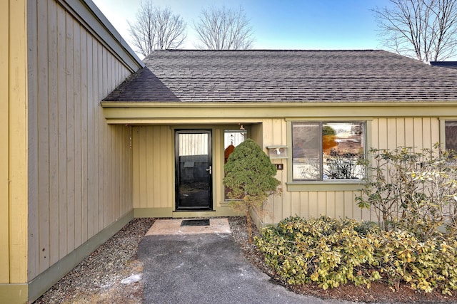 doorway to property featuring roof with shingles