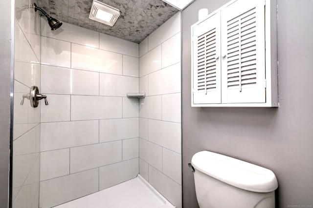 full bathroom featuring a tile shower and toilet