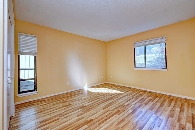spare room featuring baseboards and wood finished floors