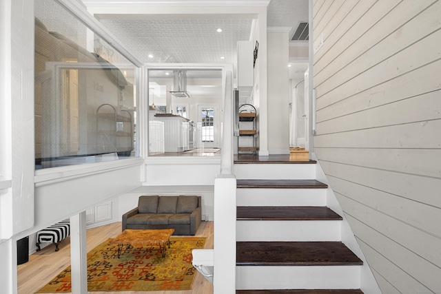 stairs featuring wood walls, visible vents, and wood finished floors