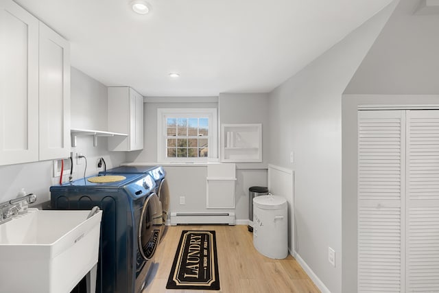 washroom featuring washer and clothes dryer, cabinet space, light wood-style flooring, a baseboard heating unit, and a sink