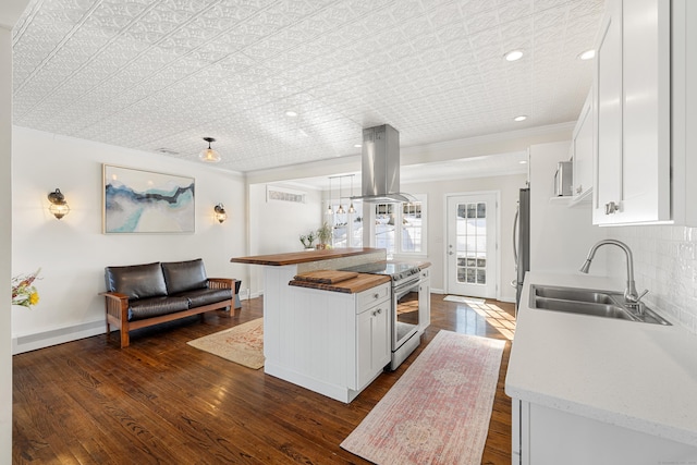 kitchen featuring electric range, island range hood, white cabinets, butcher block counters, and a sink