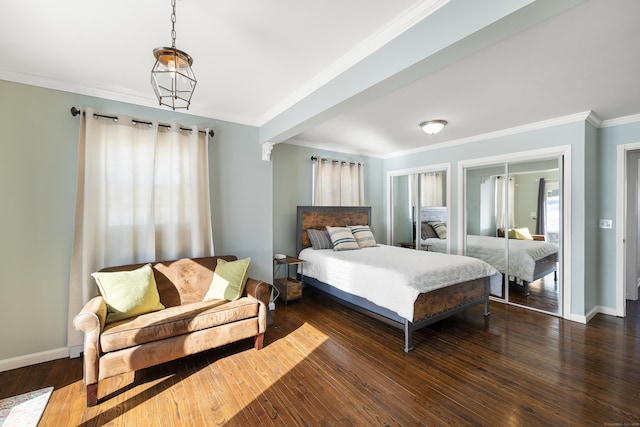 bedroom with crown molding, two closets, baseboards, and wood finished floors