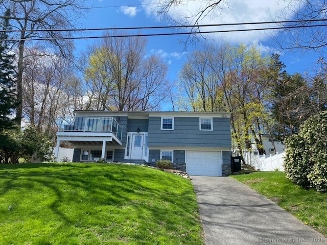 split foyer home featuring a garage, a front yard, fence, and aphalt driveway