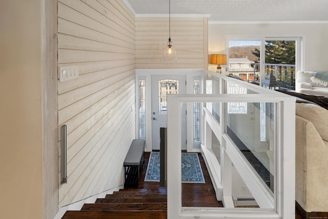 staircase featuring ornamental molding, wooden walls, a textured ceiling, and wood finished floors