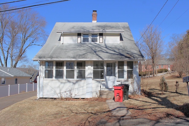 view of front of property with a chimney, a tile roof, fence, and a sunroom