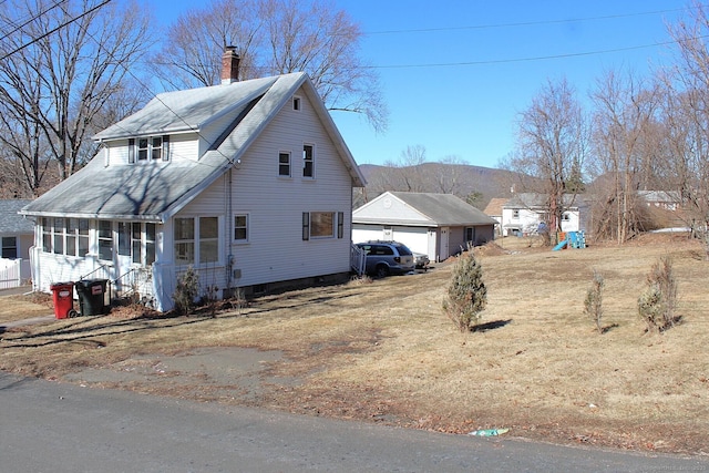 view of home's exterior with a sunroom, a chimney, a detached garage, roof with shingles, and an outdoor structure