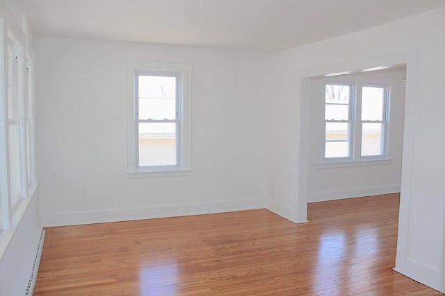 spare room featuring a baseboard radiator, light wood-style flooring, and baseboards