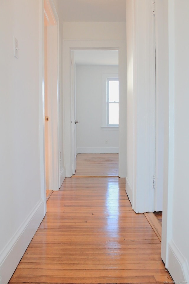 hallway with light wood finished floors and baseboards