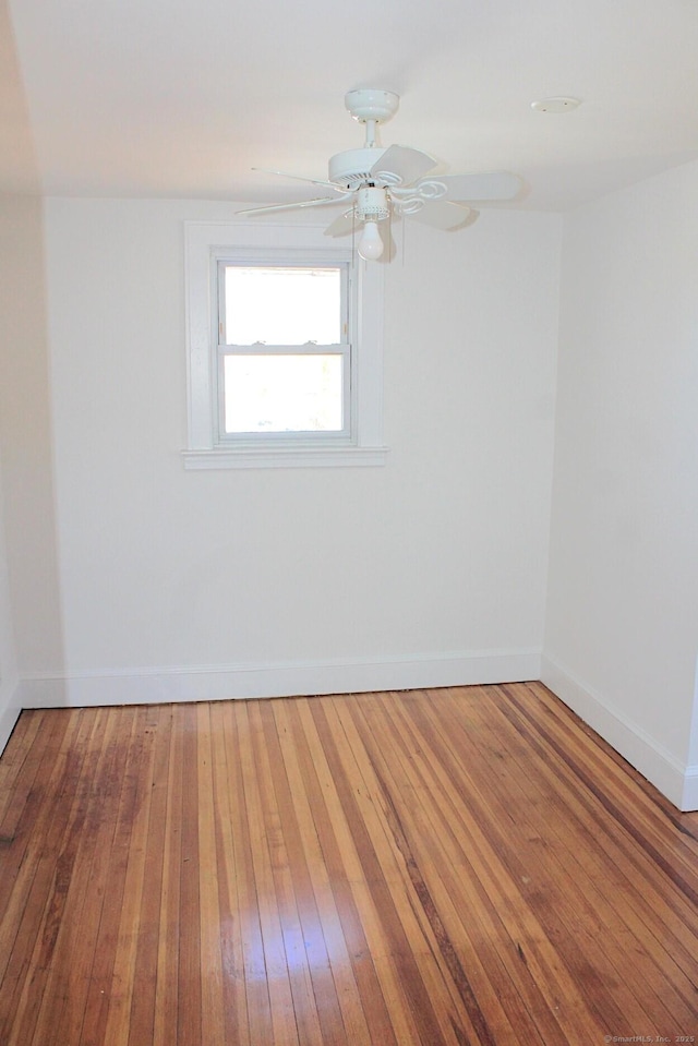 unfurnished room featuring a ceiling fan, baseboards, and hardwood / wood-style flooring