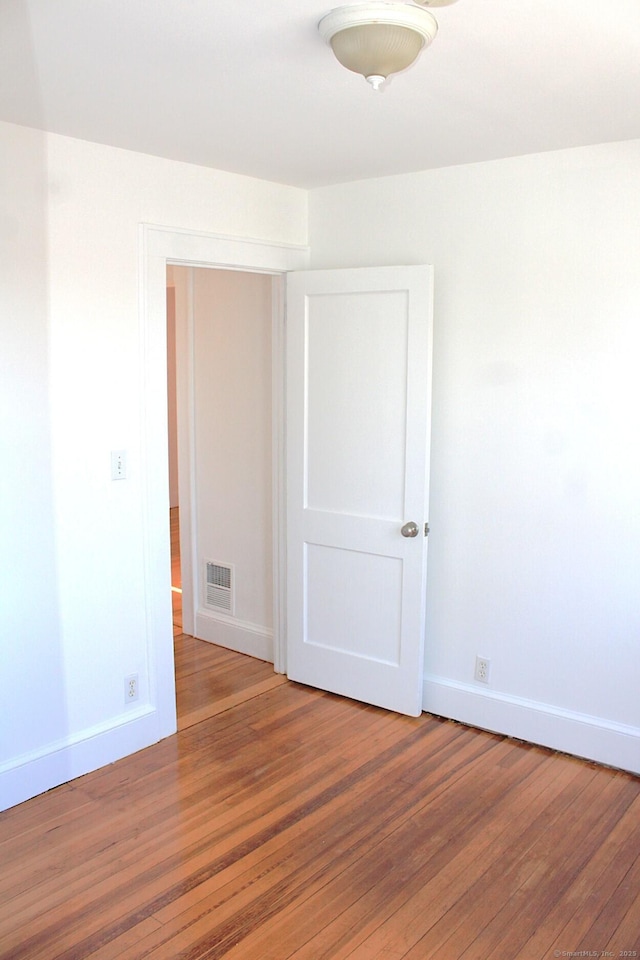 empty room with light wood-type flooring, visible vents, and baseboards