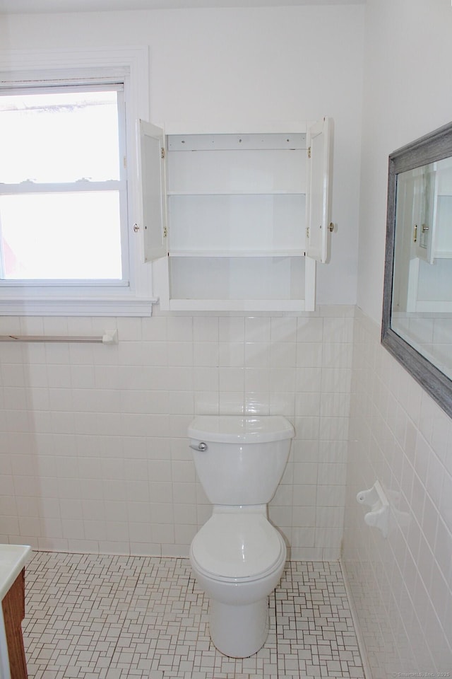 bathroom with tile patterned flooring, wainscoting, tile walls, and toilet