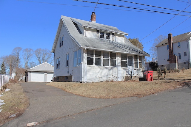 view of front of home featuring a chimney, entry steps, a sunroom, a garage, and an outdoor structure