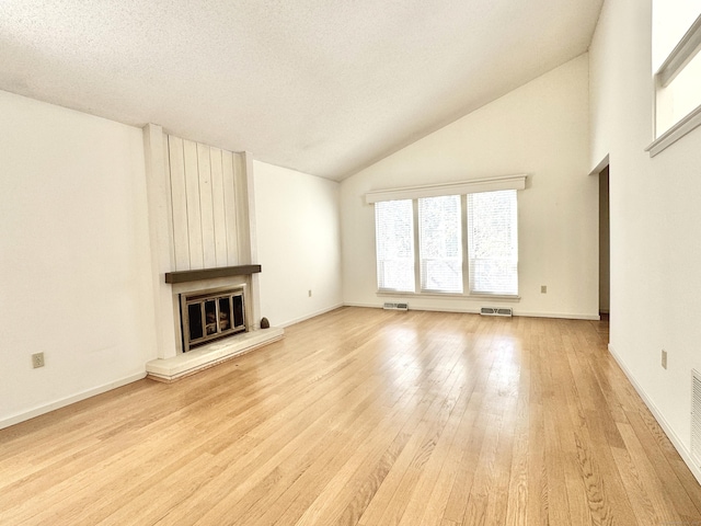 unfurnished living room with a large fireplace, a textured ceiling, visible vents, and light wood-style floors