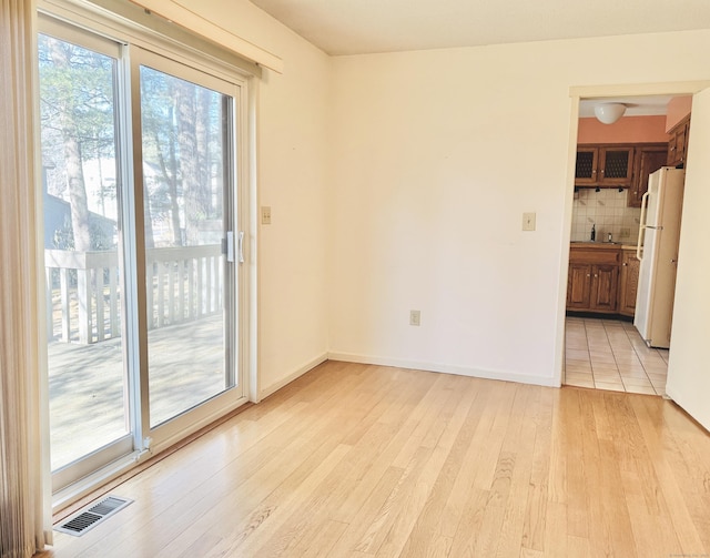 spare room with visible vents, light wood-style flooring, and baseboards