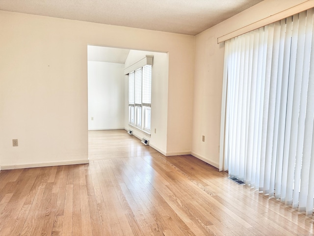 unfurnished room featuring baseboards, visible vents, and light wood finished floors