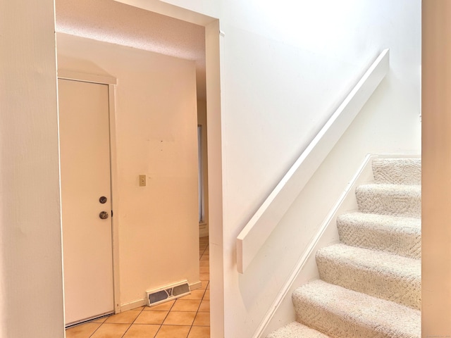 stairway featuring visible vents and tile patterned floors