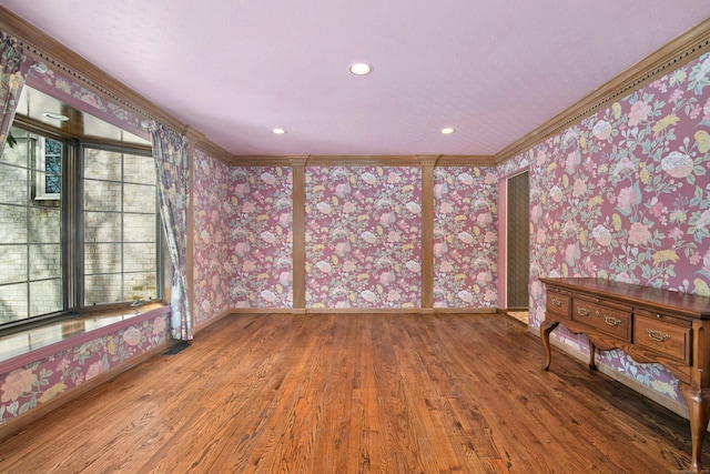 unfurnished room featuring baseboards, ornamental molding, wood finished floors, and wallpapered walls