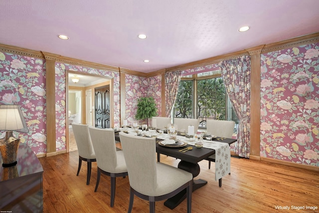 dining area featuring wallpapered walls, crown molding, and wood finished floors