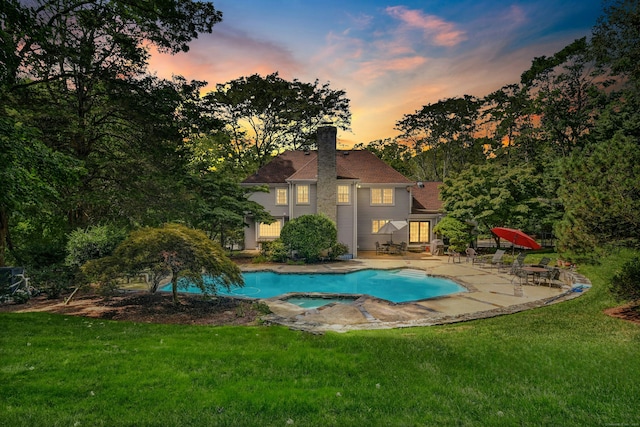 view of swimming pool with a patio, a lawn, and a pool with connected hot tub