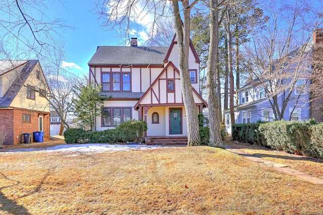 english style home with roof with shingles, a chimney, and stucco siding