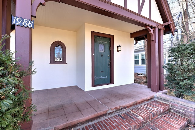 view of exterior entry featuring a porch and stucco siding