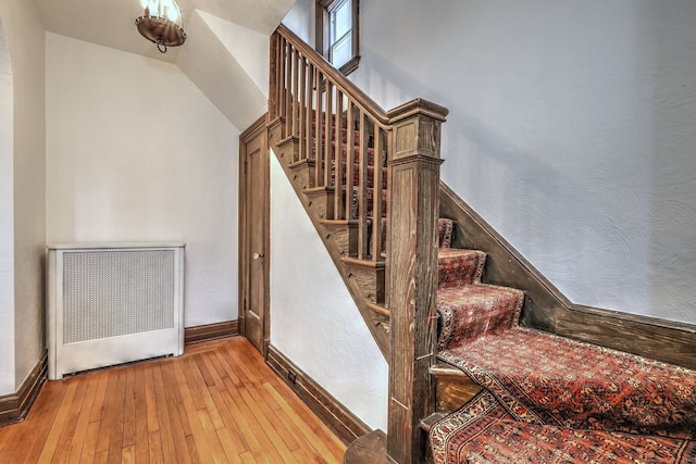 staircase with radiator, wood-type flooring, and baseboards