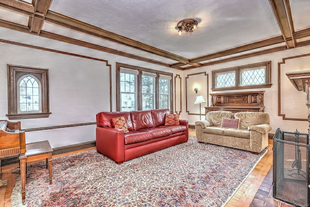 living room featuring beam ceiling, coffered ceiling, wood-type flooring, and a wealth of natural light