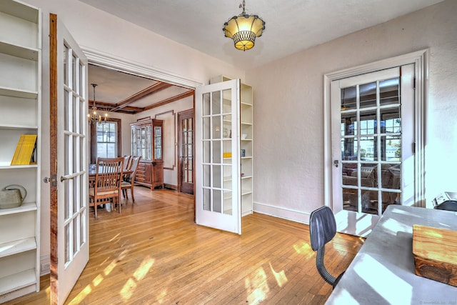 office area featuring a textured wall, baseboards, french doors, wood-type flooring, and an inviting chandelier