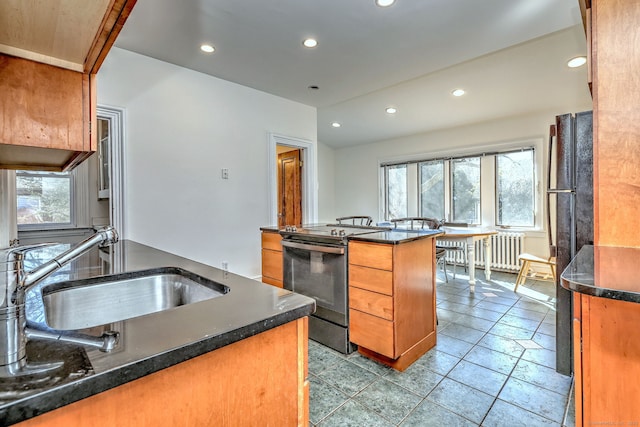 kitchen featuring stainless steel electric range oven, brown cabinetry, a sink, and recessed lighting