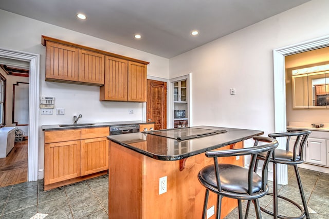 kitchen featuring a breakfast bar area, a kitchen island, a sink, dishwasher, and stovetop