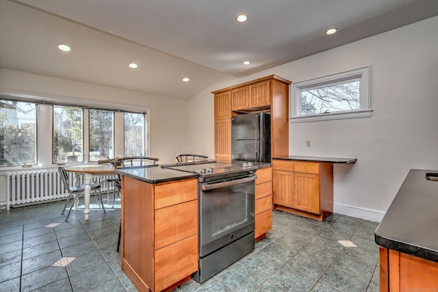 kitchen featuring a healthy amount of sunlight, freestanding refrigerator, stainless steel electric stove, radiator, and dark countertops