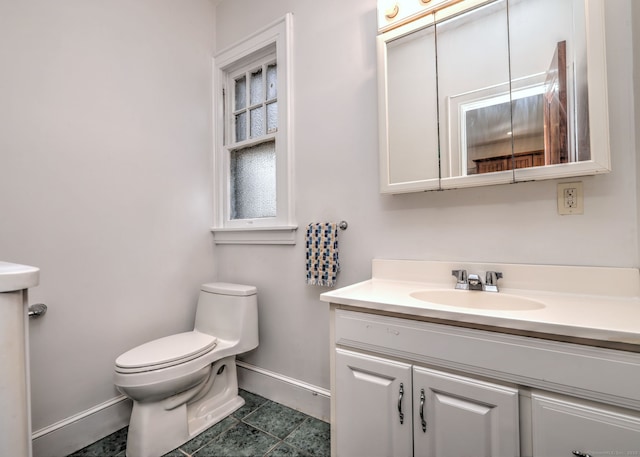 half bathroom with toilet, tile patterned flooring, baseboards, and vanity