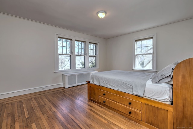 bedroom featuring radiator, wood-type flooring, and baseboards