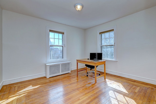 office with radiator heating unit, light wood-type flooring, and baseboards