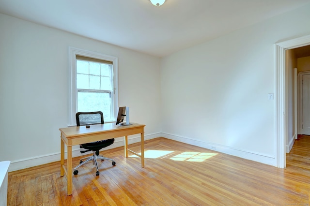 home office with light wood-type flooring and baseboards