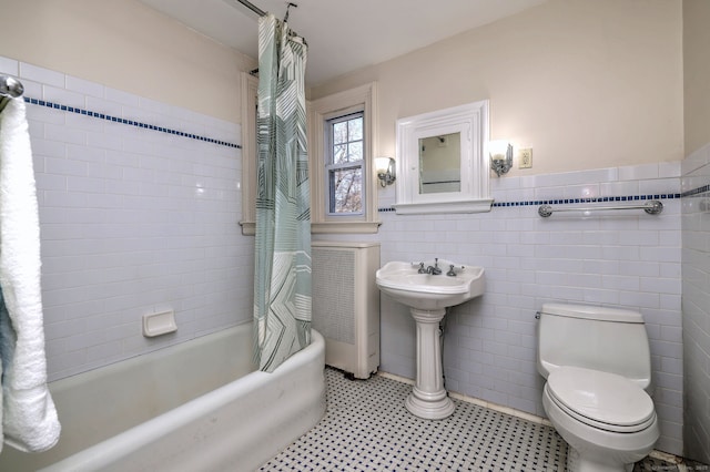 full bathroom featuring wainscoting, toilet, tile patterned floors, shower / bath combo with shower curtain, and tile walls