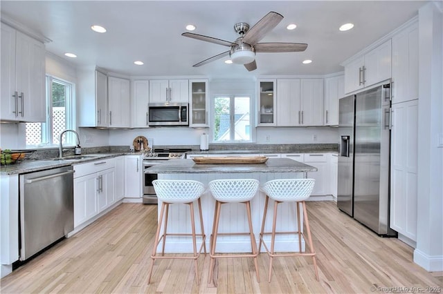 kitchen with light wood-style flooring, white cabinetry, stainless steel appliances, and a sink