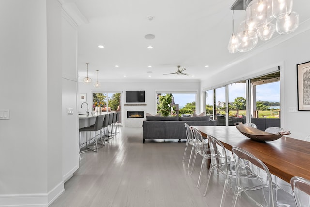 dining room with recessed lighting, a ceiling fan, a glass covered fireplace, and plenty of natural light