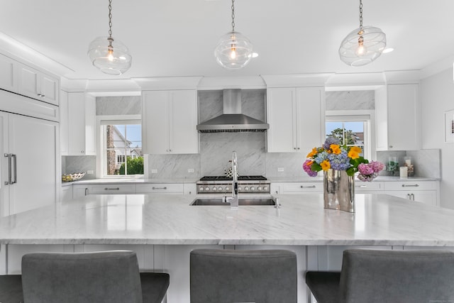 kitchen featuring wall chimney exhaust hood, white cabinets, and a sink
