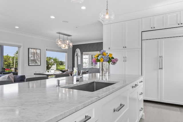 kitchen featuring a sink, white cabinetry, ornamental molding, and a healthy amount of sunlight