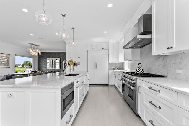 kitchen with crown molding, a sink, built in appliances, white cabinets, and wall chimney exhaust hood