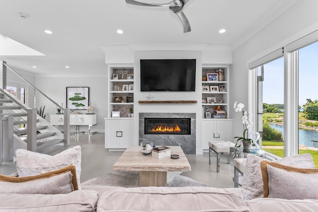 living room with built in shelves, a premium fireplace, a ceiling fan, and finished concrete flooring