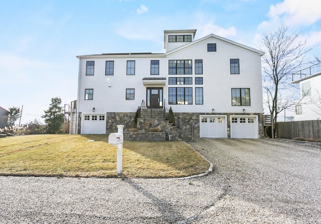 view of front facade featuring a garage, a front yard, and gravel driveway