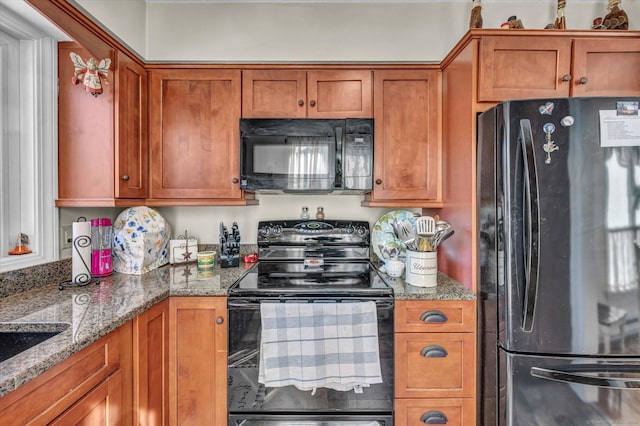 kitchen with black appliances, brown cabinetry, and light stone countertops