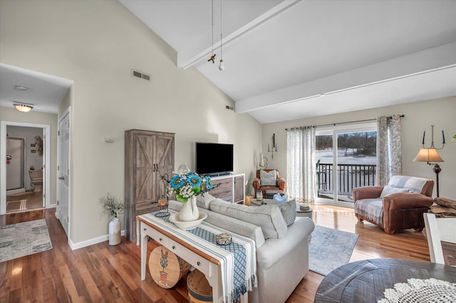 living area with high vaulted ceiling, visible vents, baseboards, and wood finished floors