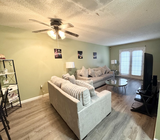 living area featuring a textured ceiling, wood finished floors, and baseboards