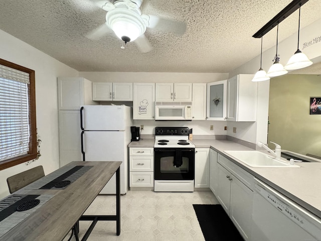 kitchen featuring white appliances, a sink, white cabinetry, light countertops, and hanging light fixtures